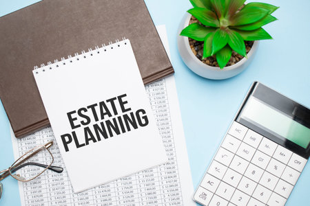 On the desktop are a calculator, diaries, a potted plant, a pen and a notebook with the text ESTATE PLANNING. Business concept. Workplace close upの写真素材
