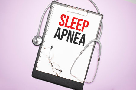 Gray stethoscope and paper plate with a sheet of white paper with text sleep apnea light blue backround. Medical concept.の写真素材