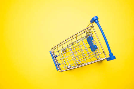 close-up of shopping trolley on yellow background with some copy spaceの写真素材