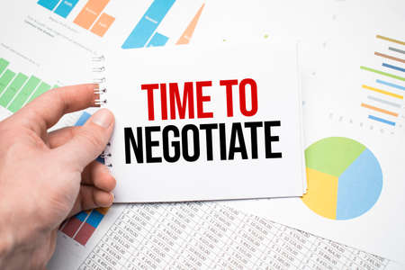Time to negotiate on a notepad and financial documents and a cup of coffee on wood table.