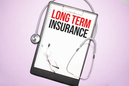 Gray stethoscope and paper plate with a sheet of white paper with text Long Term Insurance light blue backround. Medical concept.の写真素材