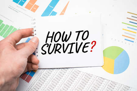 How to survive on a notepad and financial documents and a cup of coffee on wood table.の写真素材