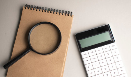 White notepad with stylish pen, magnifying glass and calculator on red, blue background. copyspace.の写真素材