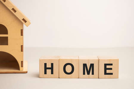 Wooden house and cube blocks spelling HOME on wood board. Concept for financial home loan or money saving for house buying.の写真素材