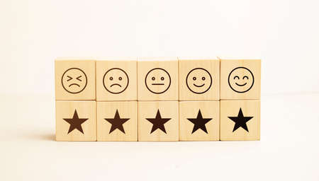 emotion face and star symbol blocks on table background. Service rating, ranking, customer review, satisfaction, evaluation and feedback conceptの写真素材