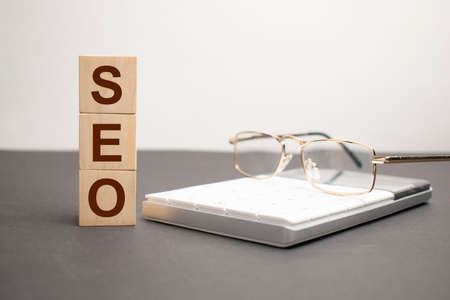 SEO word written on wood block with chart, glasses and pencilsの写真素材