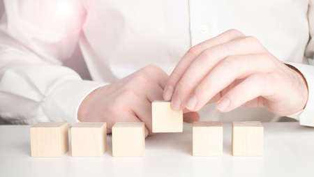 Hand holding blank wooden block cubes on table background, business concept background, mock up,...