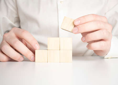 Hand putting and stacking blank wooden cubes on table with copy space for input wording and infographic icon.の写真素材