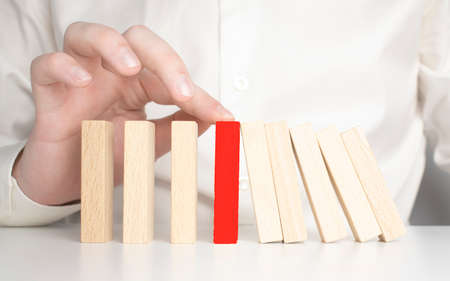 close-up hand The hand of a businessman who is stopping or preventing a falling block.Risk...