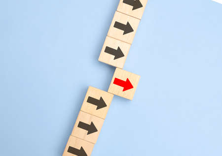 Wooden blocks with arrows with one moving forward and standing out from the crowd. Concept of...