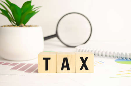 wooden cubes with letters TAX on white table with keyboard and glassesの写真素材