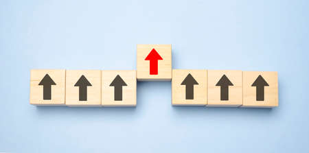 Wooden blocks with arrows with one moving forward and standing out from the crowd. Concept of...