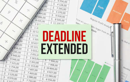 business and finance concept. Phrase DEADLINE EXTENDED written on notebook with a pen,calculator,coins and fake money.の写真素材