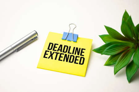On the desktop there are reports, notepads, a calculator, a cash and a red sticker with the text DEADLINE EXTENDED. business conceptの写真素材