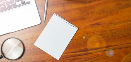 Notepad, laptop, eye glasses, magnifying glass with green plant and pen on a white wooden background. workplace. Copy space, flat lay. Concept business and finance.の写真素材