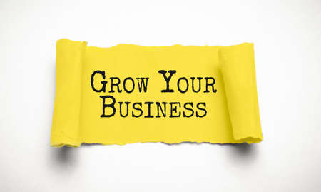 The text GROW YOUR BUSINESS appearing behind torn brown paper. high quality photoの写真素材