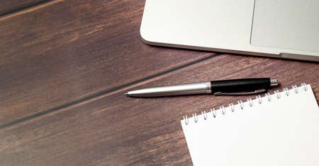 Online education concept Blank notebook with laptop and pen on wooden table top view