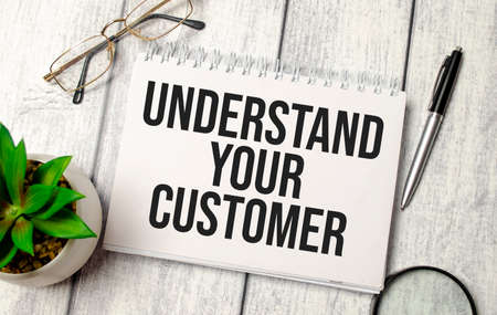 Notebook with text UNDERSTAND YOUR CUSTOMER sheet of white paper for notes, calculator, glasses,の写真素材