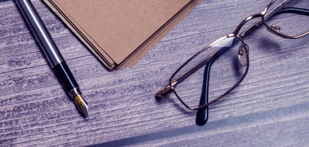 Notepad, pen and glasses on wooden desk. business conceptの写真素材
