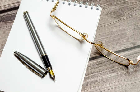 Wood office desk table with blank notebook on the wooden tableの写真素材
