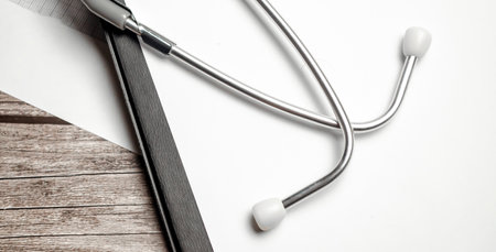 Stethoscope in doctors desk and paper folder on wooden backgroundの写真素材