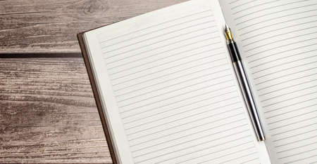 Notepad, pen and glasses on wooden desk