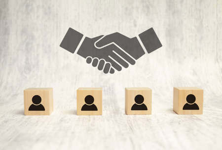 handshake icon screen on wooden cube block over employees wooden backgroundの写真素材