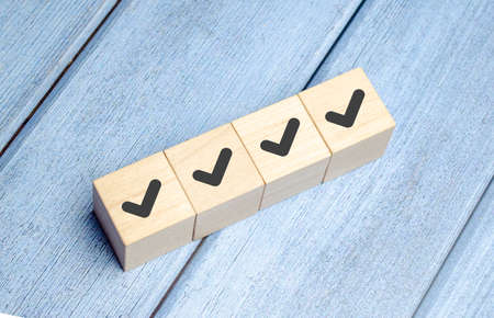 Checklist and check mark concept. Check mark on wooden blocks on light blue background