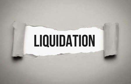 liquidation word on white torn paper. bankruptcy conceptの写真素材