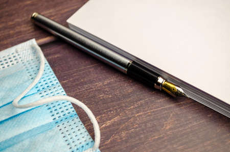 Notebook and pen for notes, next to a medical protective mask,の写真素材