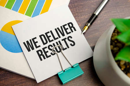 business concept. Notebook with text WE DELIVER RESULTS on chartsの写真素材