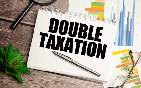 DOUBLE TAXATION words on notepad with magnifying glass and chartsの写真素材