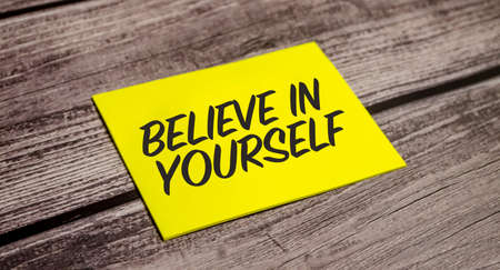 Believe in yourself concept. Yellow paper and wooden backgroundの写真素材