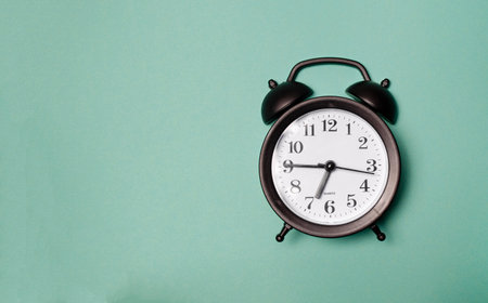Classic black alarm clock on the green bed sheets