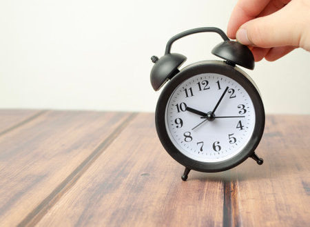 sets the alarm, man's hands set the time and set the alarm on black vintage alarm clocks