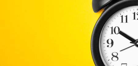 Ringing twin bell vintage classic alarm clock on yellow pastel paperの写真素材