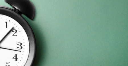 Ringing twin bell vintage classic alarm clock on green pastel paper