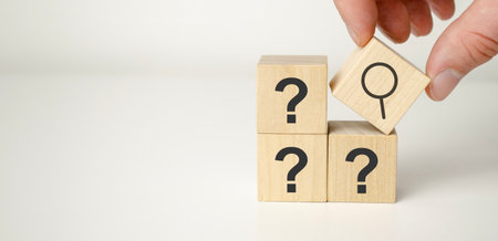 Hand hold magnifying glass and question mark sign icon in wooden cube.