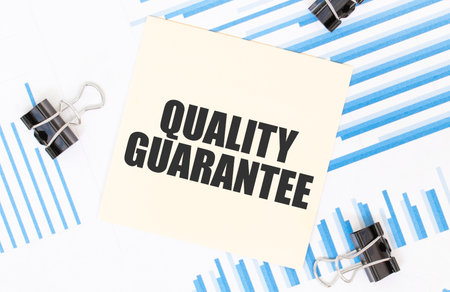 Yellow sticky notes with text quality guarantee on the white office desk. business concept.の写真素材