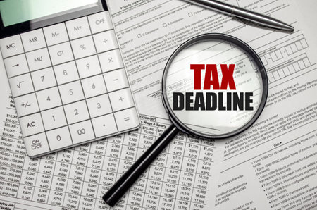 TAX DEADLINE word on magnifying glass with calculator and documentsの写真素材