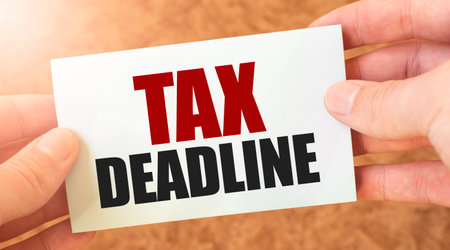 TAX DEADLINE word description on white card paper sheet in hands of a businessman.の写真素材