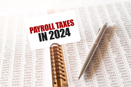 Text PAYROLL TAXES IN 2024 on paper card, pen, financial documentation on tableの写真素材