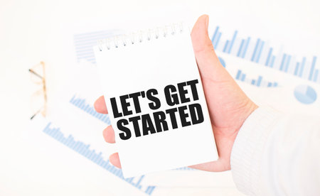 Businessman holding a white notepad with text LET's GET STARTED, business conceptの写真素材