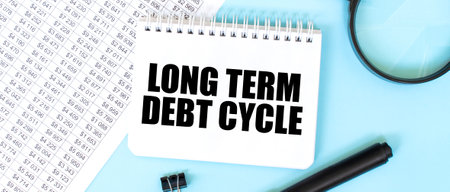 White notepad and magnifier on the financial documentation. Text LONG TERM DEBT CYCLE. Business conceptの写真素材