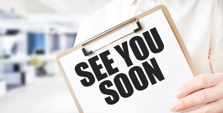Text SEE YOU SOON on white paper plate in businessman hands in office. Business conceptの写真素材