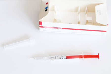 Used dose of Interferon injectable solution in pre-filled syringe for the treatment of Hepatitis C, next to plastic cap and carton box. Text translation: '180 micrograms'の写真素材