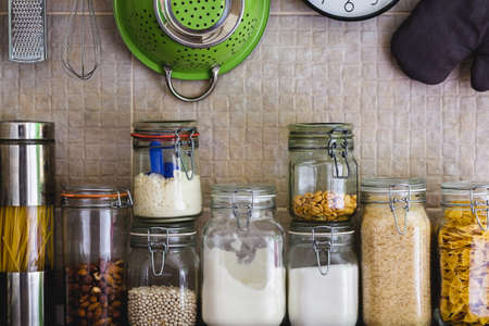 Jars with ingredients and hanging cooking utensils in the kitchenの写真素材