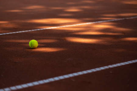 Tennis ball on a court between lines and spots of lightの写真素材