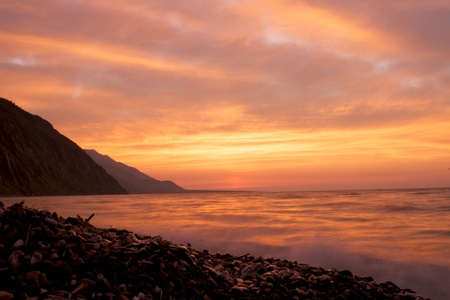 Pebble beach on the shore of Lake Baikal, the cloudy sunset skyの写真素材