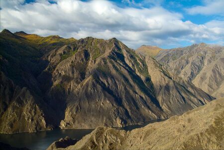 Mountain peaks with autumn forest and lake with clear blue waterの写真素材
